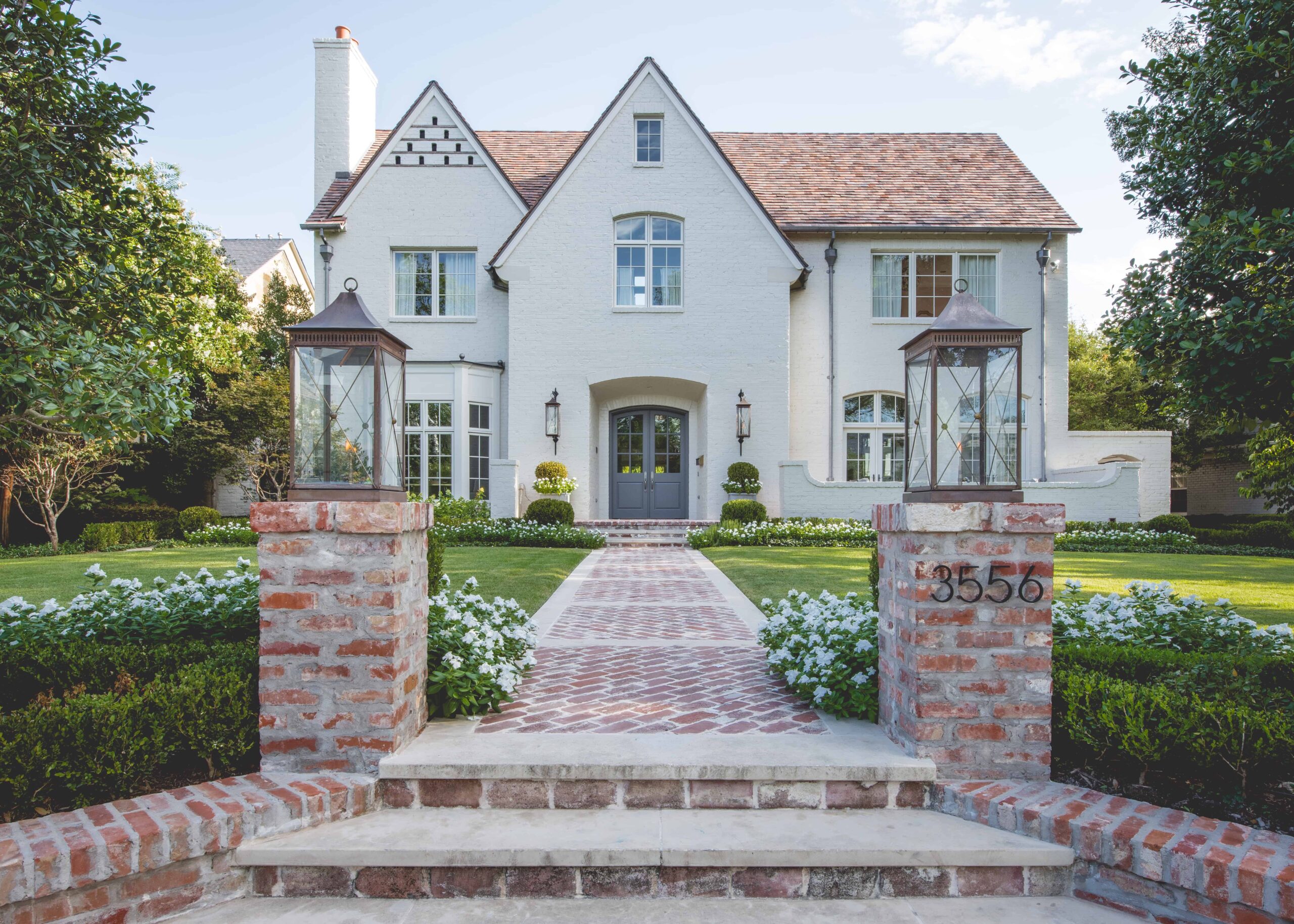 Copper gas lantern sit atop brick columns and welcome guests from the street to the front entry.