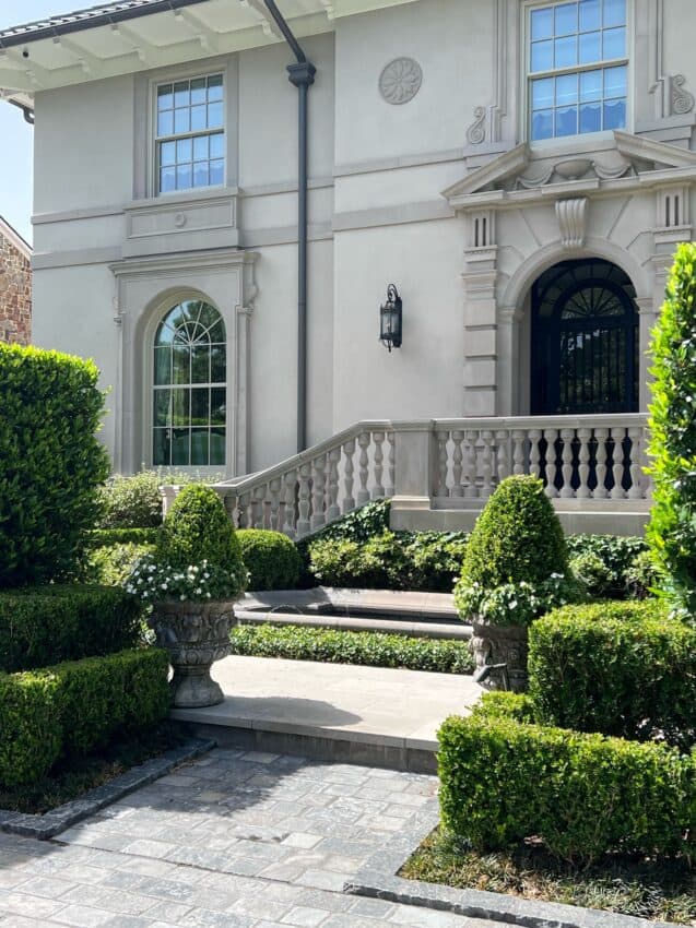 Black granite cobblestone entry with potted boxwood entering a courtyard garden with fountain